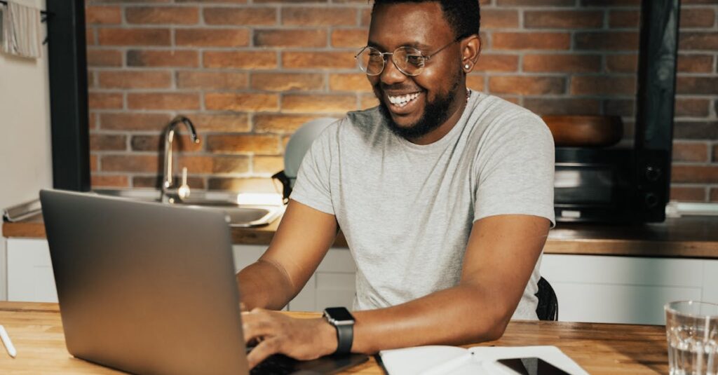 African American man smiling while working remotely on laptop from home office